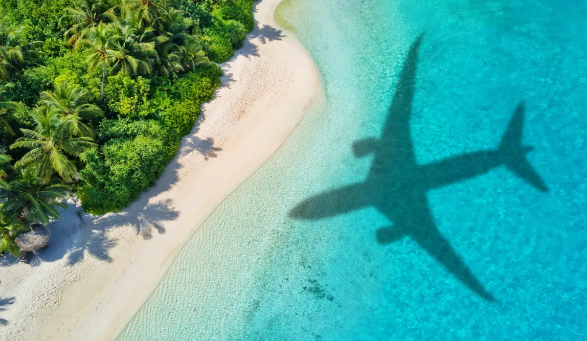 Casino Sky tropisch strand met vliegtuig schaduw boven turkoois water